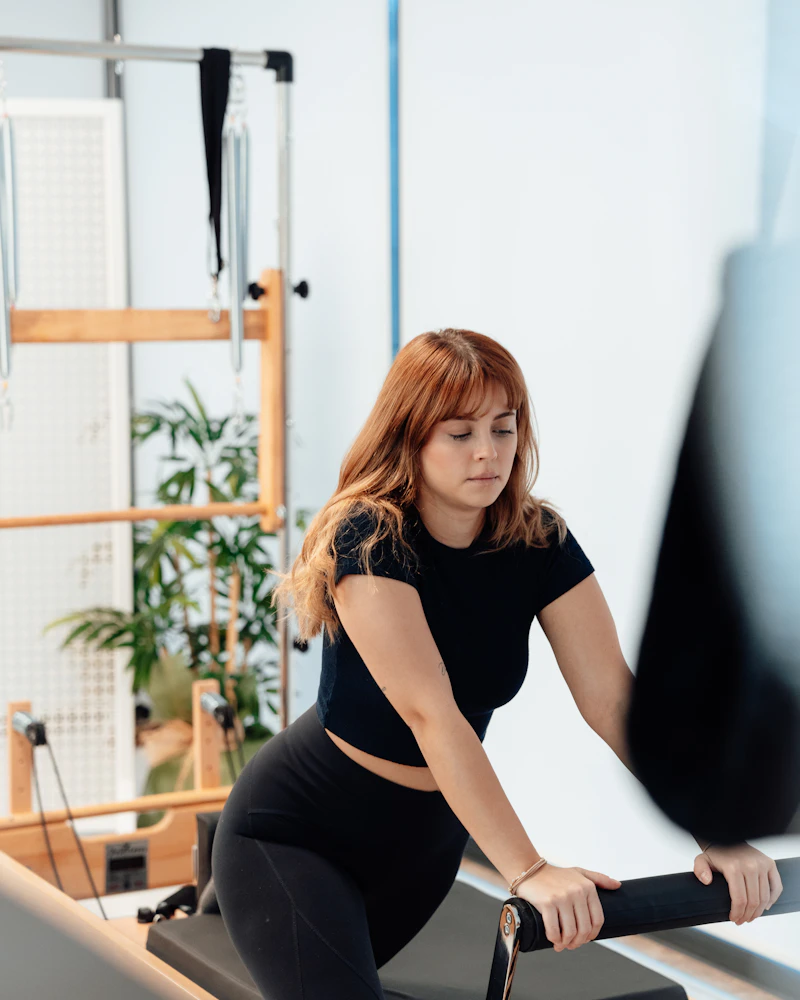 Coach de Pilates sur un Reformer dans un studio lumineux